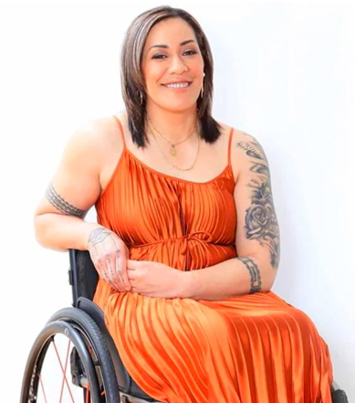AJ Pouoa in orange dress in wheelchair